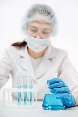 Coronavirus testi yapan eldivenli doktor şişedeki sıvıyla eline odaklanıyor.