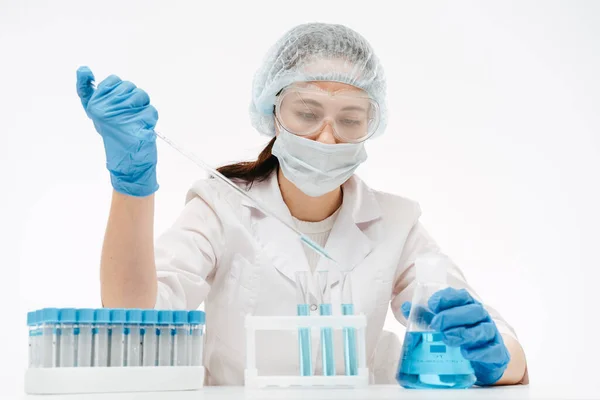 Maskeli ve gözlüklü kadın laboratuarda koronavirüs testi yapmak için örnek alıyor.