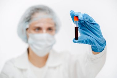 klinikte koronavirüs testi için kan tutan renkli eldivenli ciddi bir işçi.