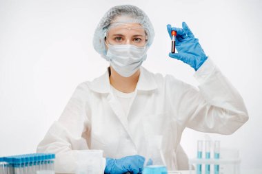 Maskeli ve gözlüklü doktor Coronavirus testi için kan örneği tutuyor.