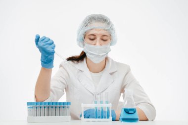 Pipetle örnek alan koruyucu maskeli asistan koronavirüs testi yapıyor