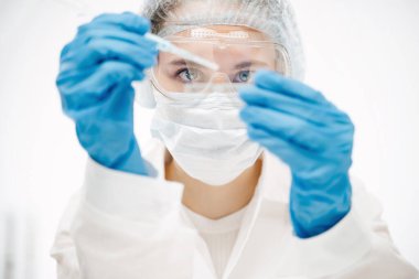 Koruyucu eldivenli genç bir kadın laboratuvarda Coronavirus testi yapıyor.