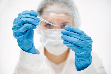 Mavi eldivenli asistan kaydırağın üzerine reaktör yerleştiriyor ve koronavirüs testi yapıyor