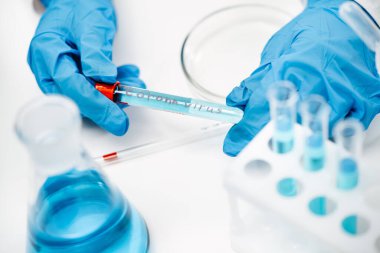 Koruyucu eldivenler giyen bilim adamı sıvı ve yazılı Covid-19 tüpü tutuyor.