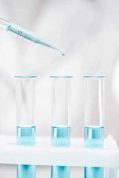 Coronavirus testi için açık mavi reaktörlü temiz cam tüpler ve pipetler.