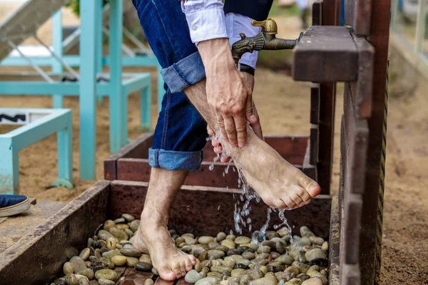Man washing his feet on the sand beach.