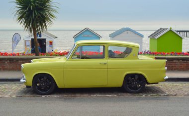 Klasik sarı Ford Anglia önünde plaj kulübe sahil yolda araba motoru.