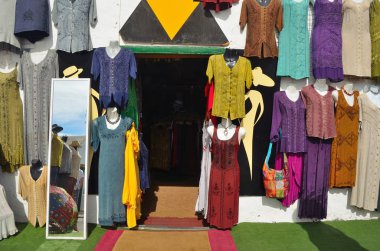  Shopfront duvar ve ayna üzerinde asılı renkli giysiler ile.