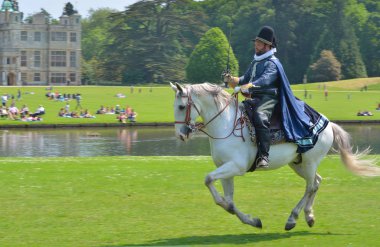  Elizabeth erkekte kostüm heybetli ev önünde dörtnala at üstünde kılıç ile.