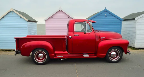 Klassieke rode Chevrolet 3100 pick-up truck op de strandboulevard tegenover strand hutten. — Stockfoto