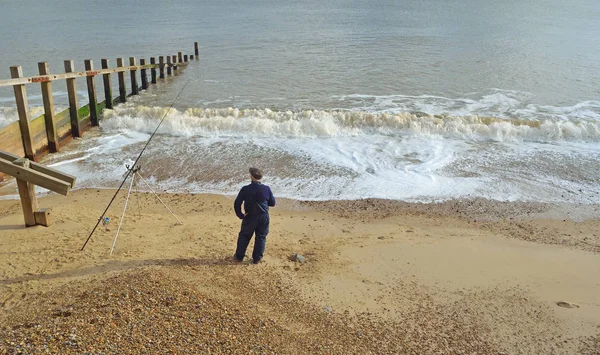 Pesca en la playa, Un hombre pescando desde la playa con caña y descanso . — Foto de Stock
