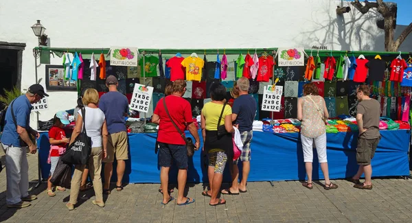 Compradores mirando la camiseta en el puesto del mercado . — Foto de Stock