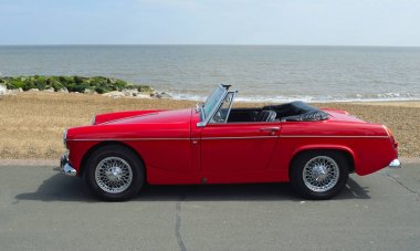 Felixstowe, Suffolk, İngiltere - 07 Mayıs 2017: Sahil mesire deniz arka planda ile klasik kırmızı Mg Roadster araba park.