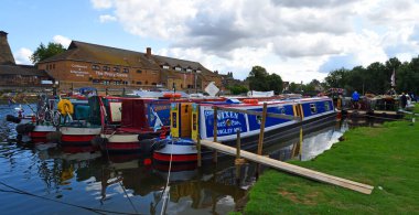 St Neots, Cambridgeshire, İngiltere - 25 Ağustos 2018: St Neots 'taki Ouse Nehri üzerindeki Dar Tekneler. Arka planda manastır merkezi var..