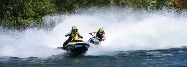 Jet Ski Racers in competitive event on lake making a lot of spray. clipart