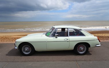 Felixstowe, Suffolk, İngiltere - 05 Mayıs 2019: Klasik Whie Mgb Gt Motor Car plaj ve deniz manzaralı deniz kenarında park halinde.