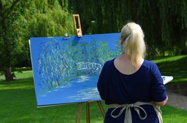 St. Neots, Cambridgeshire, İngiltere - 03 Ağustos 2019: Parkta resim yapan genç kadını kapatın.