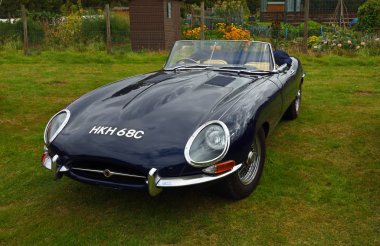 Yukarı Dekan, Bedfordshire, İngiltere - 07 Eylül 2019: Klasik Koyu Mavi 1965 Jaguar E Tipi Üstü açılır araba çimenlere park edilmiş..