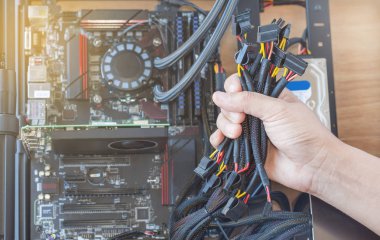 Güç bağlantısı kabloları güç kaynağının bilgisayar üzerinde tutan el