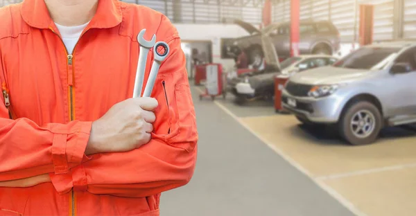 Mechanic holding wrench in car garage — Stock Photo, Image