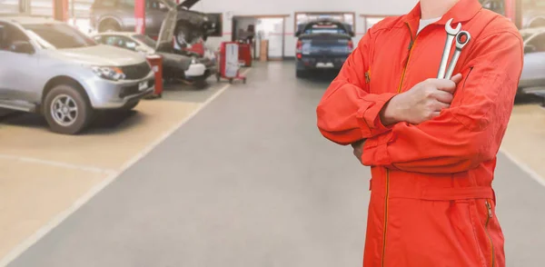 Mechanic holding wrench in car garage — Stock Photo, Image