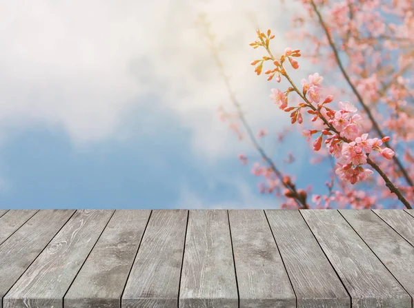Sakura çiçek ve güneş ışığı arka plan ile boş eski ahşap masa