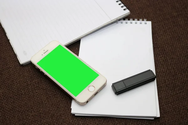 Smartphone com tela verde e notepads — Fotografia de Stock