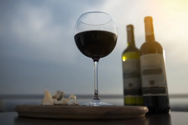 Two bottles of red french wine with wineglass and cheese; — Φωτογραφία Αρχείου