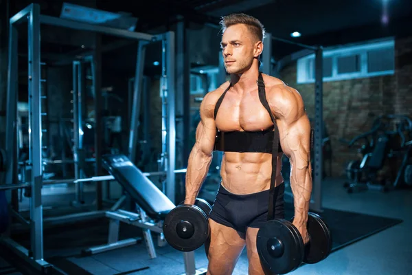 Young sportsman has workout and lift dumbbells; — Stock Photo, Image