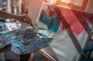 Kadın ressam fırça ve yağlı boya ile resim yapıyor.