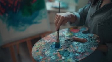 Kadın ressam fırça ve yağlı boya ile resim yapıyor.