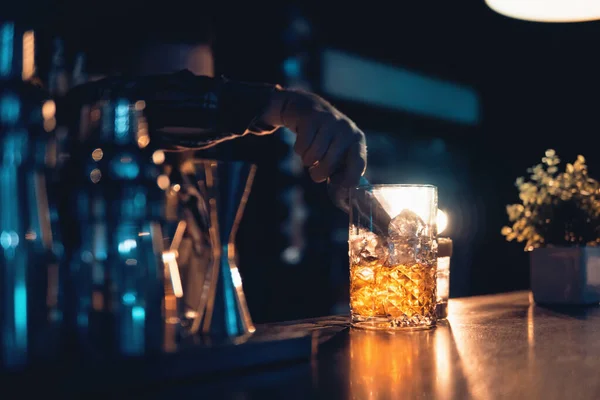 Barmen kulüpte mavi arka planda kokteyl hazırlıyor.