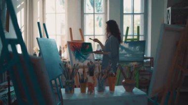 Kadın ressam fırça ve yağlı boya ile resim yapıyor.