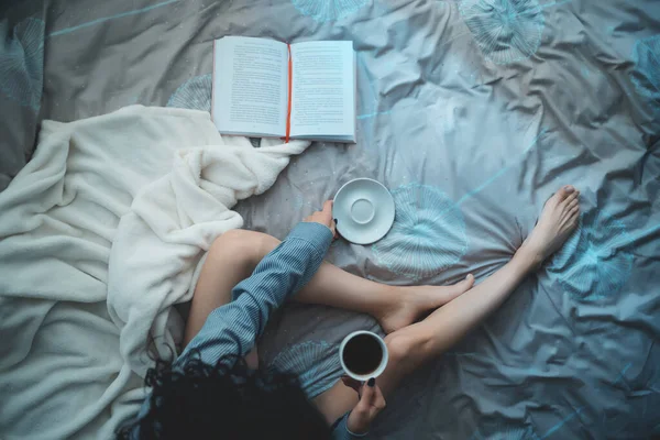 Красива брюнетка в ранковому ліжку з книгами та кавою — стокове фото