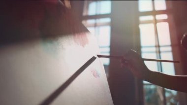 Kadın ressam pencere kenarına fırça ve yağlı boya ile resim yapıyor.