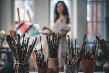 Kadın ressam fırça ve yağlı boya ile resim yapıyor.