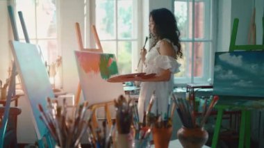 Kadın ressam fırça ve yağlı boya ile resim yapıyor.