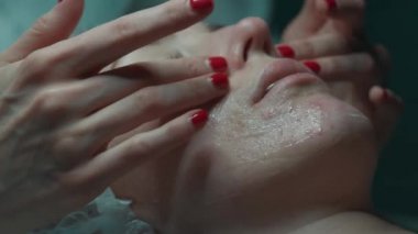 Güzellik uzmanı genç bir bayana yüz masajı yapıyor.