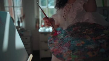 Kadın ressam fırça ve yağlı boya ile resim yapıyor.