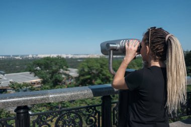 Genç turist gezici gözlem dürbününe bakıyor