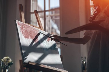 Kadın ressam fırça ve yağlı boya ile resim yapıyor.