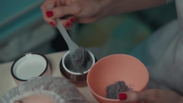 Esteticista aplicando e misturando máscara preta de alginato facial para mulher — Vídeo de Stock