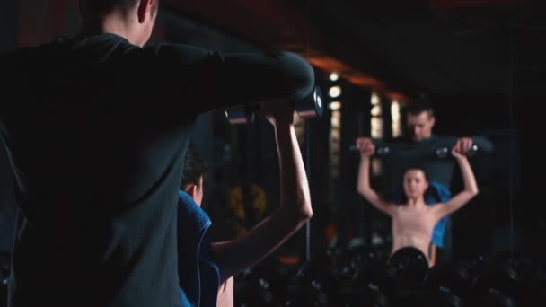 Personal trainer com mulher fitness exercitando com halteres no ginásio — Vídeo de Stock