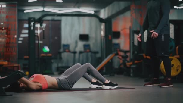 Personal trainer with woman exercising with fitness ball in gym — Stock Video