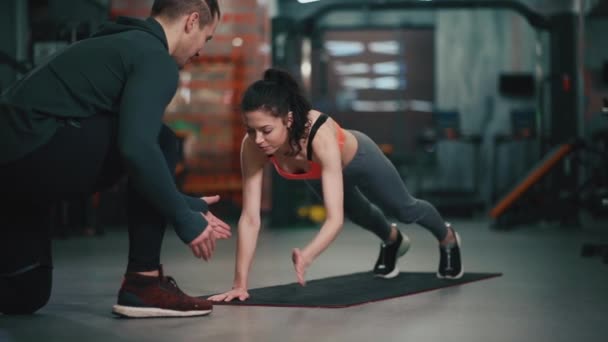 Entrenador personal con mujer fitness haciendo ejercicio en el gimnasio — Vídeos de Stock