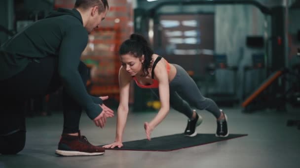 Personal trainer com mulher fitness exercitando-se no ginásio — Vídeo de Stock