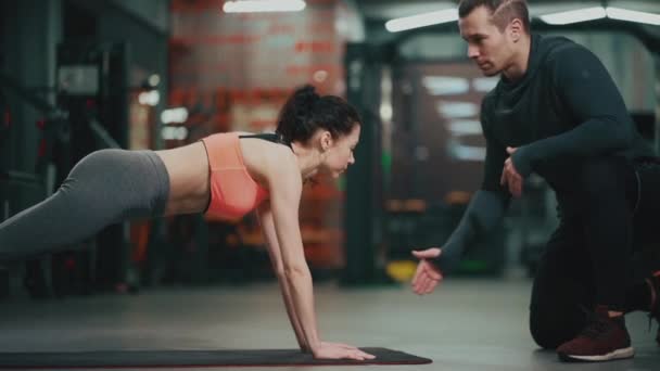 Personal trainer met fitnessvrouw in de sportschool — Stockvideo