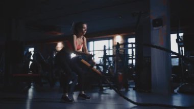 Modern spor salonunda kişisel antrenörle ip egzersizi yapan atletik kadın.