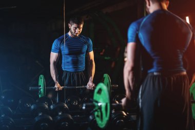 young athlete has physical workout with barbell in modern gym