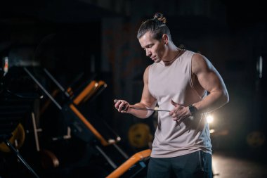 young cheerful personal trainer in gym and with clipboard and stopwatch